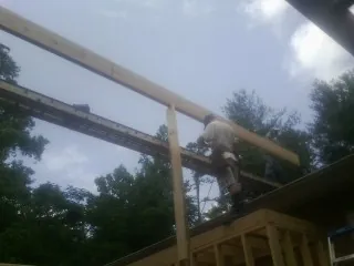 Carpenter setting a ridge beam over a new addition frame — Ice Dam Removal by Roofing Brothers in Pond Eddy