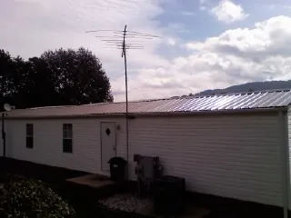 New metal roof on a single wide mobile home with a TV antenna in Pond Eddy