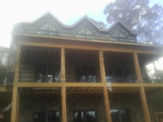 Dormers and porch framing on a large log home under construction — Roof Coating work by our crew in Pond Eddy