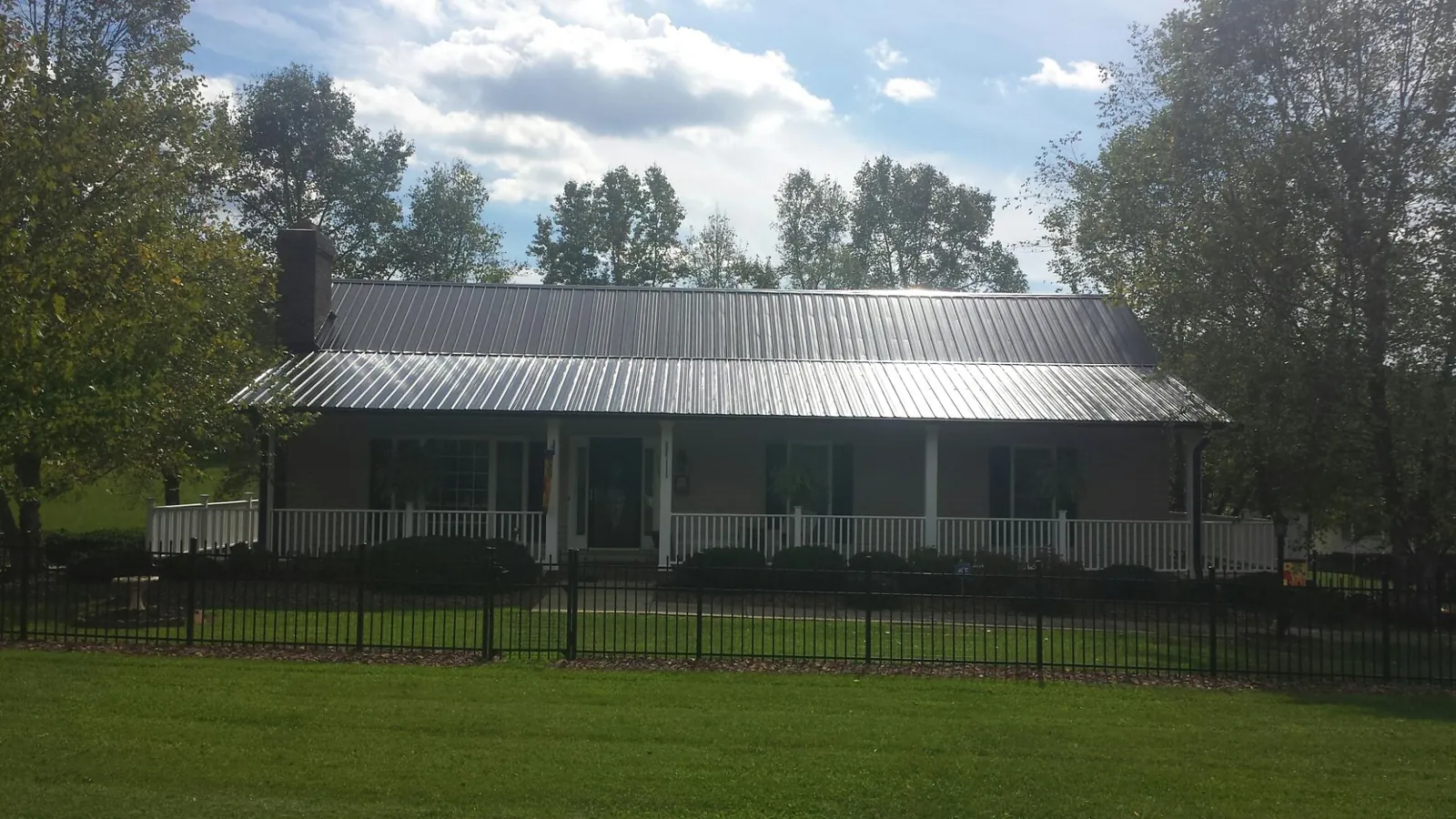 Gray metal roof on a brick ranch with a full width front porch — Gutter Guard Installation work by our crew in Pond Eddy
