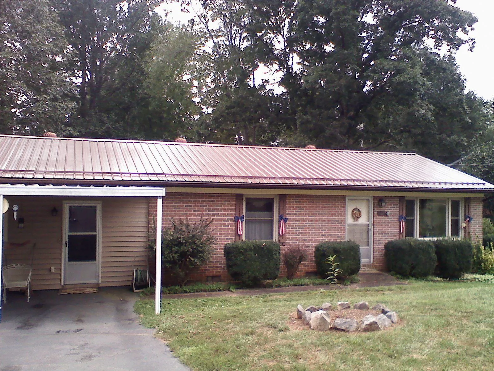Bronze metal roof and carport on a brick ranch home — Roof Repair work by our crew in Pond Eddy