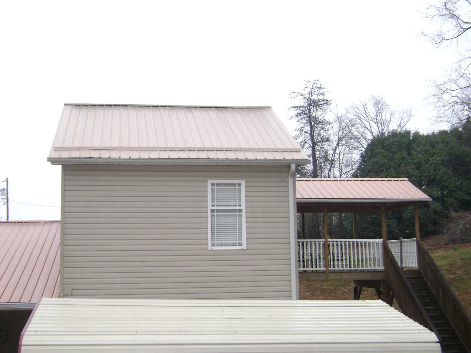 Tan metal roofs on a two story addition and attached porch, from a Roof Replacement job in Pond Eddy