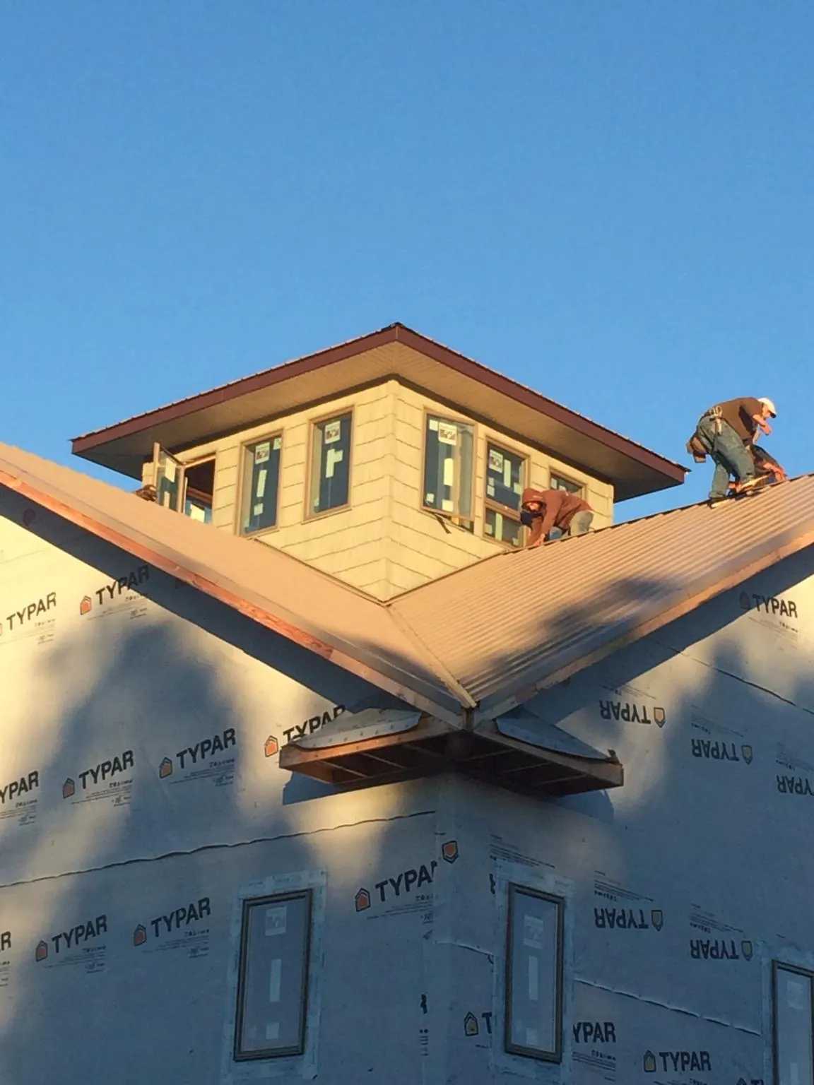 Roofers working around a rooftop cupola on a new metal roof at sunset — Roof Waterproofing in Pond Eddy by Roofing Brothers